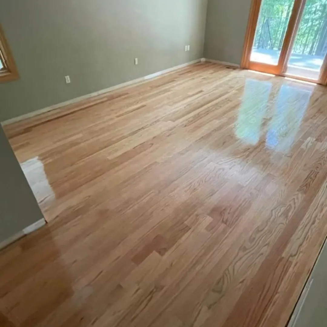 Newly refinished hardwood floors in a sunlit room.