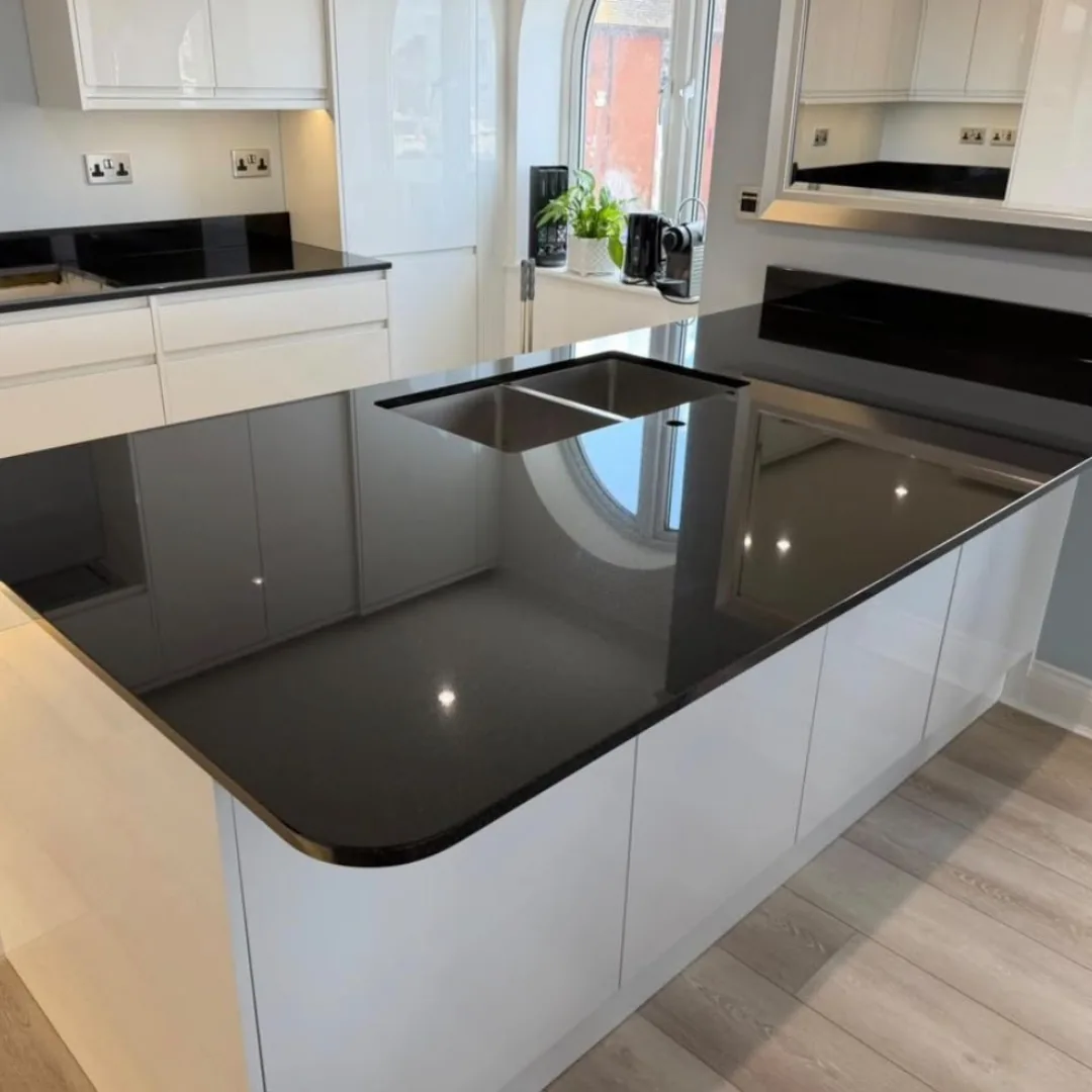 Black granite kitchen island with white gloss cabinets and an integrated cooktop