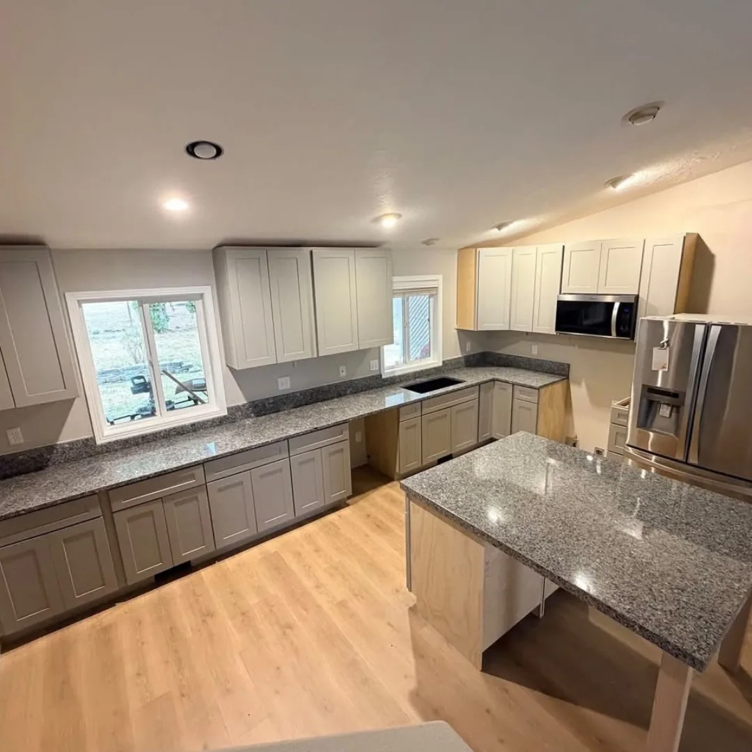 Gray kitchen cabinets with a granite peninsula countertop and hardwood floor