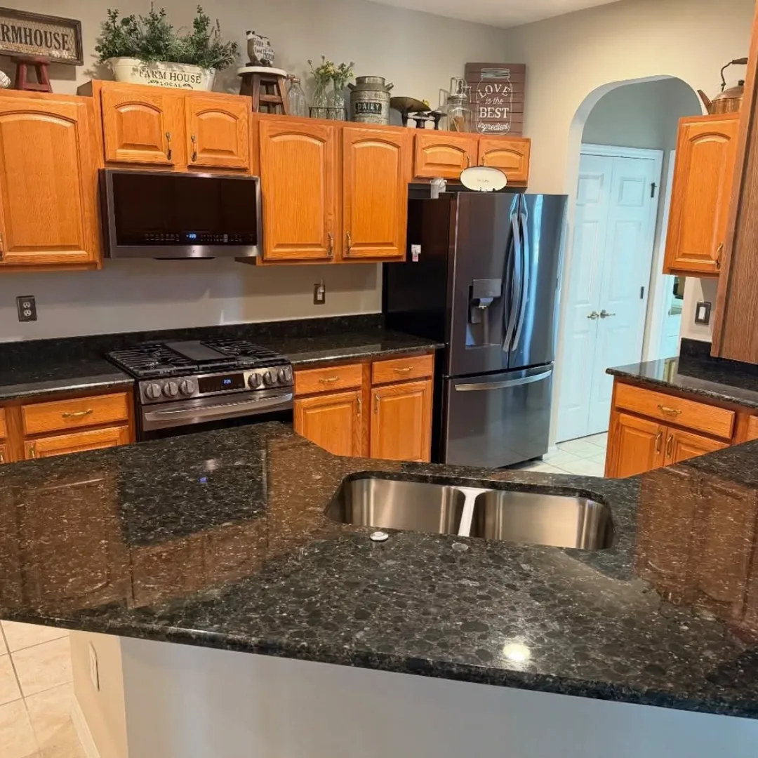 Oak kitchen cabinets with dark granite countertops and an undermount sink