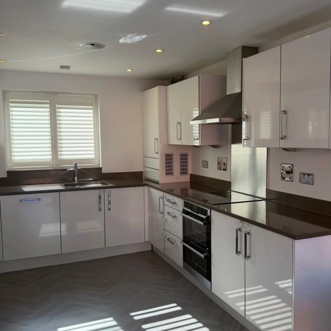 White and gray kitchen with dark countertops and plantation shutters
