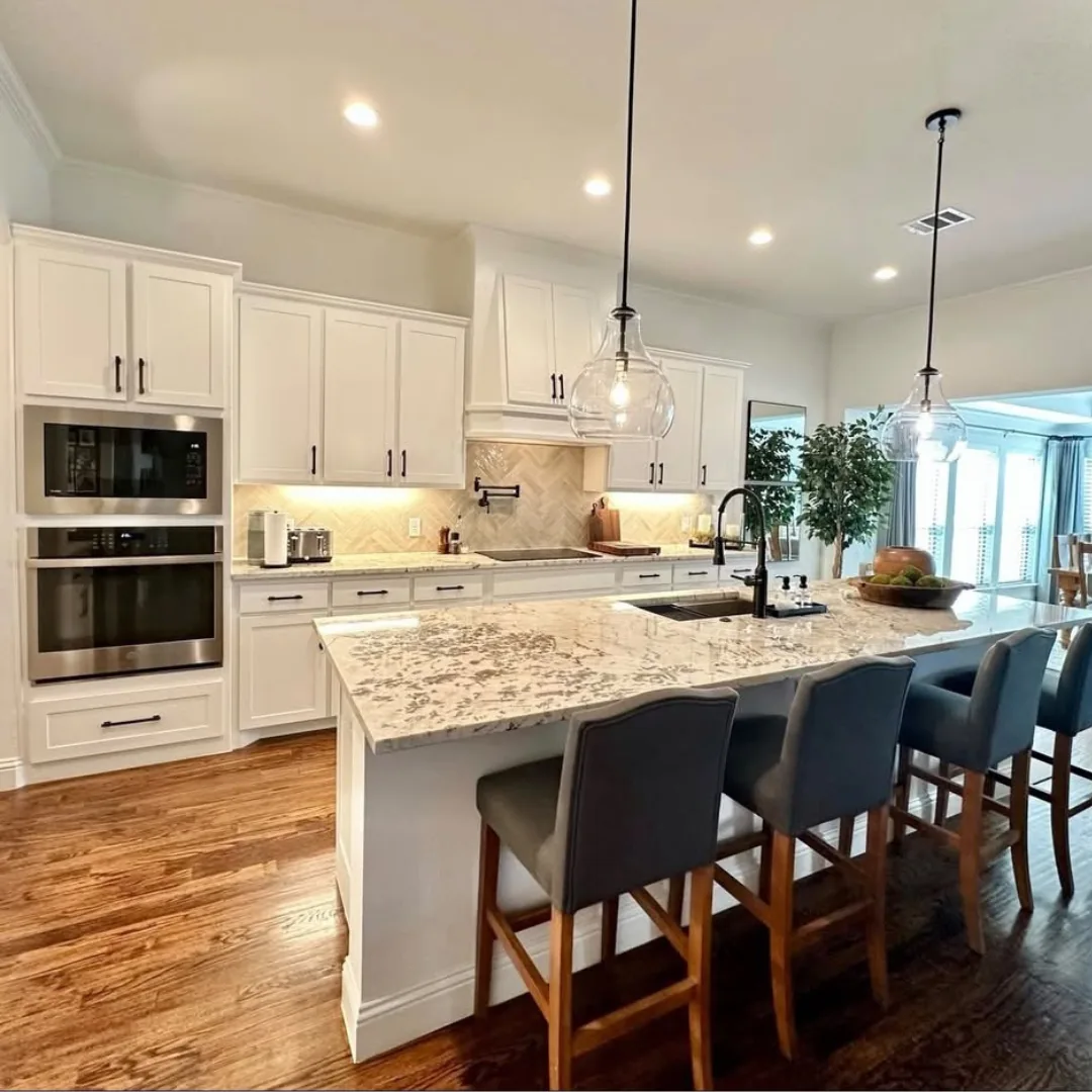 White kitchen with granite island, bar stools and refinished hardwood flooring