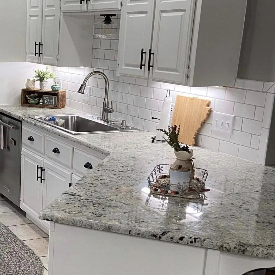 White kitchen with subway tile backsplash and a granite island countertop